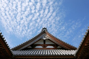 Fototapeta premium 青空と白い雲が広がる日本の歴史的な寺社建築の瓦屋根