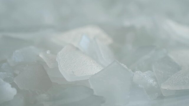 Crystalline bischofite flakes, natural magnesium chloride mineral salt, in macro view, use in spa treatments, cosmetology, balneotherapy, skincare routines. Cosmetic bischofite magnesium salt flakes