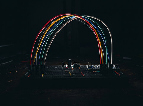 Symmetrical arch of colorful jumper wires on dark electronic breadboard for creative tech.