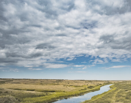 Steppe river flowing through the wild steppes of Kazakhstan in summer under cloudy skies; steppe landscape for background