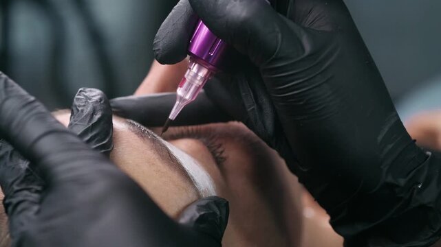 Macro close up of a permanent makeup needle with black pigment during an eyebrow tattoo procedure in a professional beauty studio.