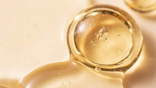 Close up of golden cosmetic serum or oil drop with bubbles