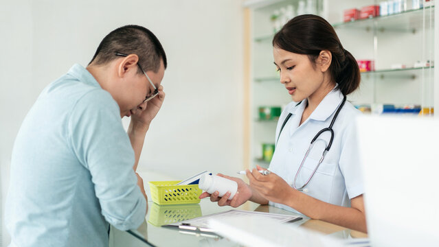A woman in a white coat is talking to a man in a blue shirt