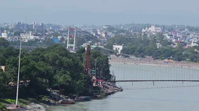 Ram Jhula spans the Ganga River in Rishikesh, with Janki Setu and a dense riverside cityscape farther downstream.