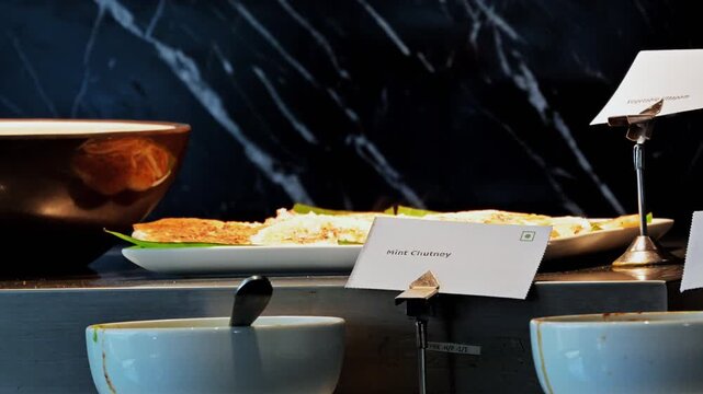 A buffet display includes serving bowls, a ladle and a Mint Chutney label at a dining venue in Rishikesh.