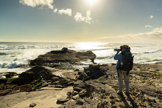 female photographer overlooking elevated view of massive wave sets rolling into Walker Bay Nature Reserve, South Africa 