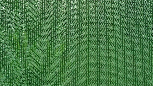 Green Shade Net Texture for Plants with Rain Drops Flowing Down Woven Mesh, Showing Sun Protection, Gardening, Weather Exposure And Water Movement