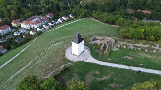 Aerial orbit around the historic chapel on Piramida Hill in Maribor, Slovenia, revealing the surrounding green slopes, woodland and cityscape.
