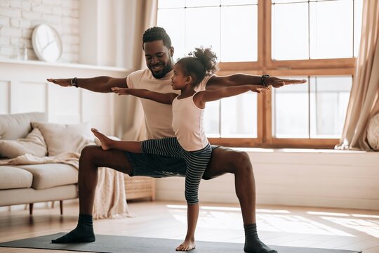 African american father and daughter doing yoga poses together in a bright living room at home