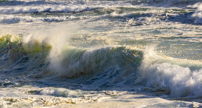 massive waves crashing into rock formations, Walker Bay Nature Reserve, South Africa at sunset.