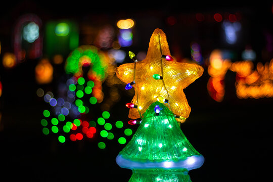 New Year's illuminated tree with garland on top on dark field, Christmas street decorations
