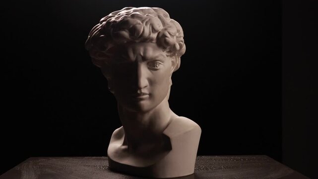Plaster bust of a classical male sculpture under dramatic side light
