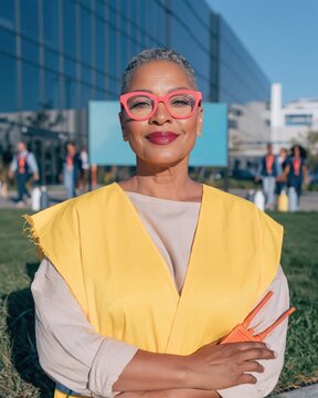 Black woman fire warden in a yellow hi-vis tabard holding an orange radio, calm and professional during a workplace safety fire drill for EHS software