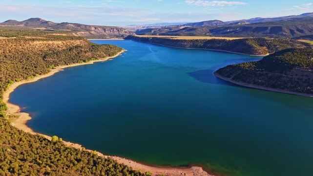 Aerial morning sunrise illuminates calm waters and foothills around Ridgway Reservoir and State Park in Colorado