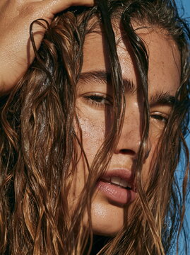 Close-Up of a Hand Skillfully Styling Wet Hair with Lustrous Shine Under Natural Light