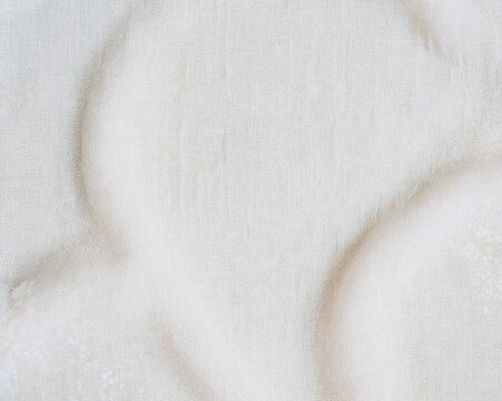 Loose weave muslin cloth with subtle green stains and crystalline residue, a textured fabric surface for home remedies and herbal remedy backgrounds