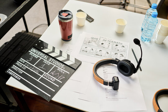 High angle shot of clapperboard, storyboard, script, and headphones on table during film preproduction. Useful for cinematography and media projects