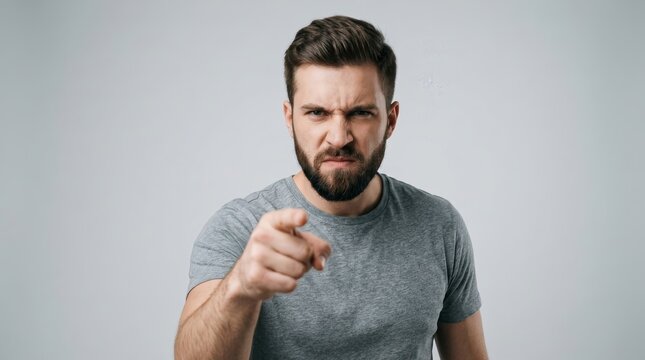 Angry young man with a beard on a gray studio background