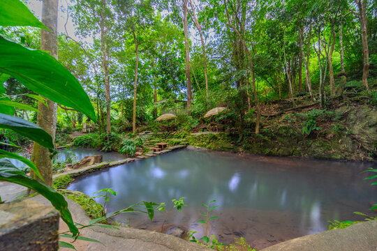 Kathu Dam waterfall water gently flowing down the rocks surrounded by lush green trees flowers and tables Patong on the Island of Phuket Thailand