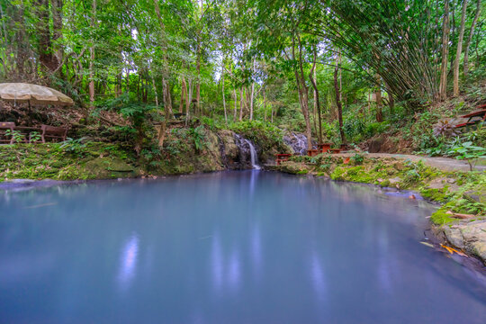 Kathu Dam waterfall water gently flowing down the rocks surrounded by lush green trees flowers and tables Patong on the Island of Phuket Thailand