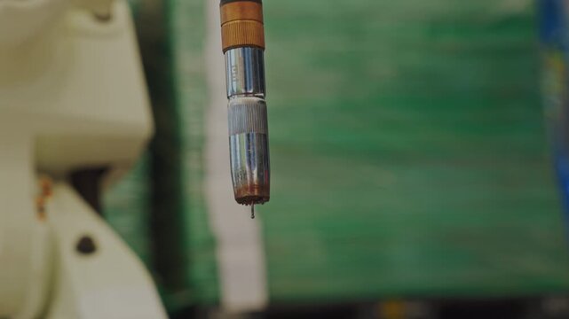 Industrial tool with metal nozzle and wooden handle in green workshop, close up detail of hanging fishing rod tip and guide against weathered wall, rustic outdoor angling equipment scene