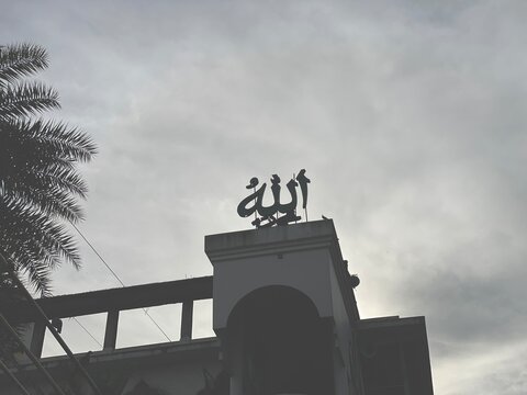 Silhouette of Islamic Mosque with Allah Calligraphy Under a Cloudy Sky