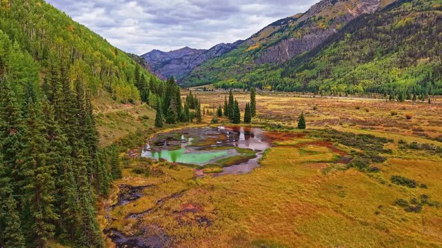 Golden autumn aspen forests and rugged mountains surround colorful mineral ponds near historic Ironton along Million Dollar Highway Colorado