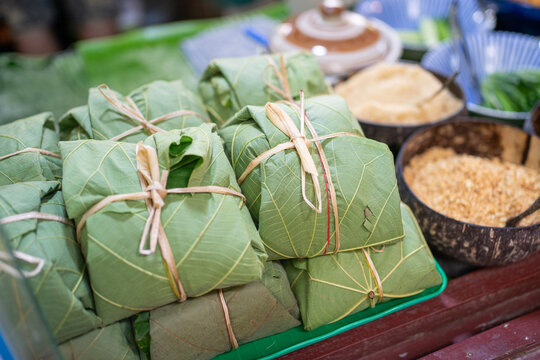 Eco-friendly street food parcels wrapped in natural green leaves and tied with plant fiber strings, sustainable zero waste food packaging concept