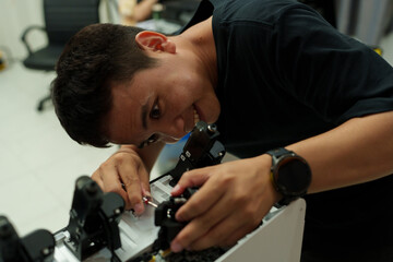 Fototapeta premium The focus is on the hands of a technician setting up a 3D printer to print a clear white plastic model, using cutting-edge technology and concentrating on specific points within the laboratory.