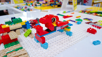 Obraz premium Red lego car vehicle built from plastic building blocks placed on white baseplate with colorful bricks on table play area on September 22, 2026 in Bangkok, Thailand.