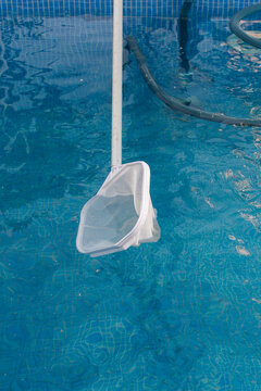 Close up of pool skimmer net collecting floating debris from swimming pool