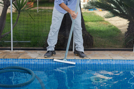 Work shoes and brush cleaning swimming pool tiles during routine maintenance