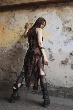 Back view of hooded woman looking over shoulder, tattered post-apocalyptic costume, grunge