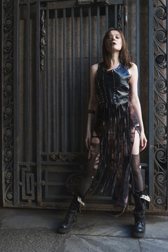 Ornate wrought iron gate and woman with closed eyes, dark urban gothic fashion, full length