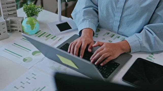 Businesswoman reviewing ESG reports and green business financial charts with a laptop and documents. ESG concept Environmental, Social, and Governance, eco-friendly green building, sustainable