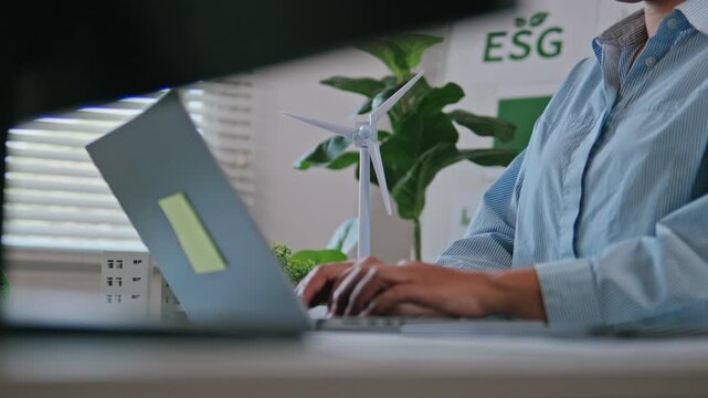 Businesswoman reviewing ESG reports and green business financial charts with a laptop and documents. ESG concept Environmental, Social, and Governance, eco-friendly green building, sustainable