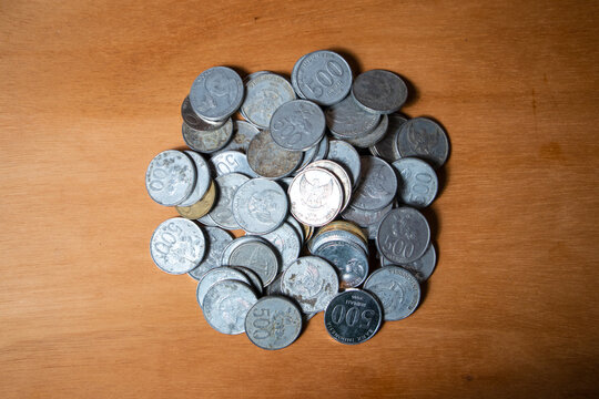 Stacked silver coins rest on warm wooden surface