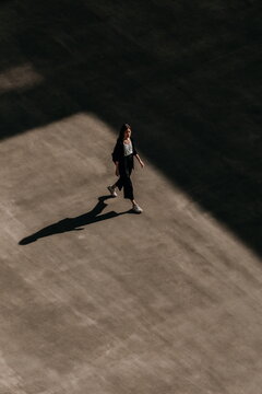 Silhouette of Individual Casting a Long Shadow on Urban Pavement During Golden Hour