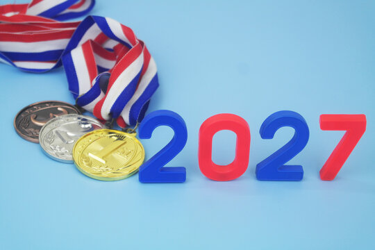 Gold, silver and bronze medal with numbers 2027 on blue background. Sport competitions in year 2027 concept.	