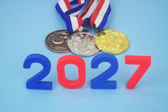 Gold, silver and bronze medal with numbers 2027 on blue background. Sport competitions in year 2027 concept.	
