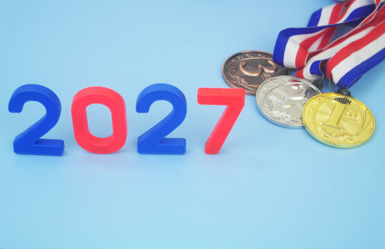 Gold, silver and bronze medal with numbers 2027 on blue background. Sport competitions in year 2027 concept.	