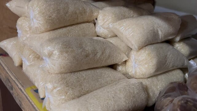 Stacked plastic bags of white granulated sugar in traditional market shop
