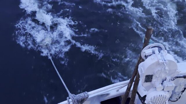 A mop trails in churning water as crew rinses it from a cruise ship along the Neva River. White foam splashes against dark waves. The simple task brings a curious and lively feeling.