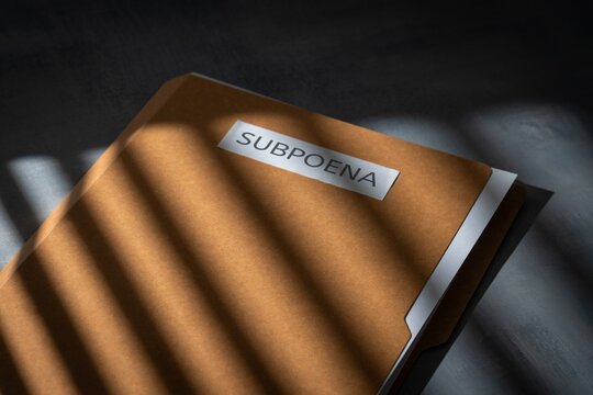 Brown file folder with a Subpoena label on a dark background. Legal investigation, courtroom litigation, corporate fraud, criminal evidence concept.