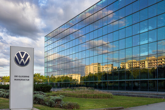Die Gl&auml;serne Manufaktur von Volkswagen zeigt sich mit spiegelnder Glasfassade unter bew&ouml;lktem Himmel. 