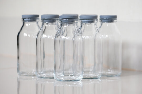 Close-up of empty clear glass bottles with grey rubber caps