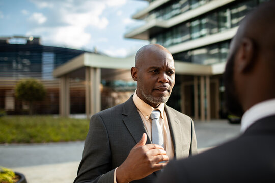 Senior businessman talking with colleague outside office building