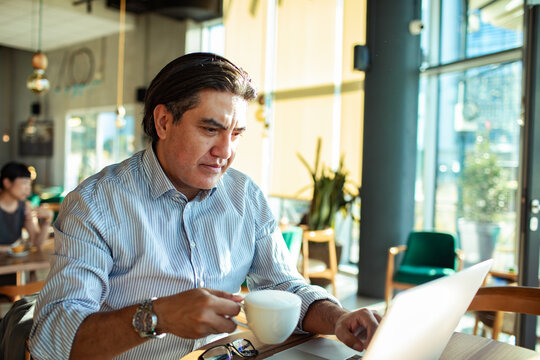 Man using laptop and drinking coffee in cafe