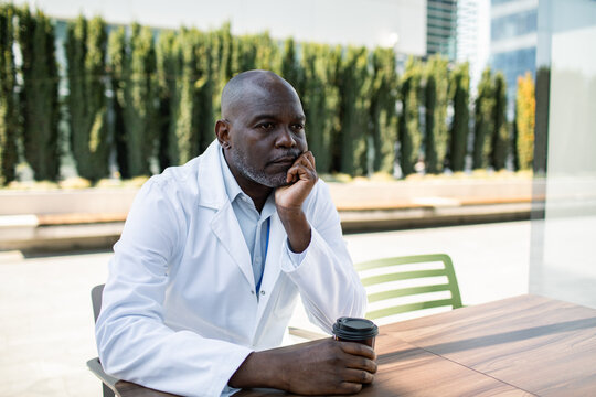 Doctor taking a coffee break outdoors looking thoughtful