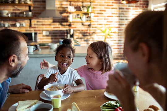 Two girls laughing at breakfast in a home kitchen